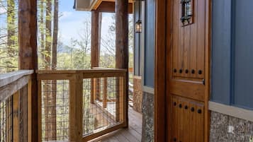 A wooden porch with a wooden door and two wall-mounted lanterns.