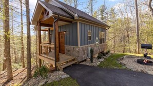 Een chalet met veranda, vuurkuil en brievenbus.