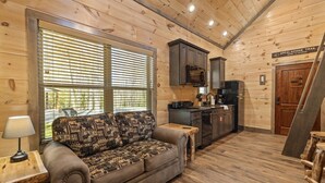Een gezellig interieur van een blokhut met een bank, houten wanden, een keukenhoek en een bordje met daarop de Appalachian Trail.