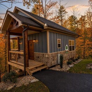 Eine Holzhütte mit einer Holterrasse, einer Veranda und einem Steinfundament.