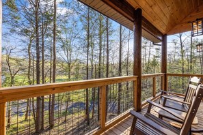 Eine Holzterrasse mit Geländer, mit Blick auf ein bewaldetes Gebiet.