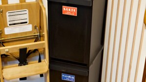 A black refrigerator with a sign indicating it is for guests, a wooden chair, and a wooden floor.