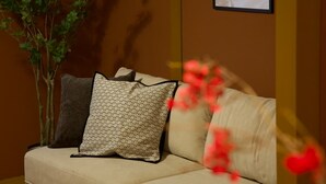 A beige sofa with patterned cushions, a potted plant, and a framed picture on the wall.