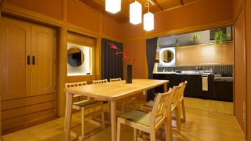 Una mesa de comedor de madera con sillas, un espejo redondo y un jarrón con flores rojas.