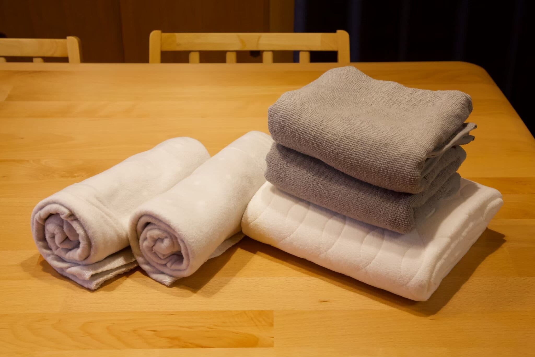 A wooden table with folded towels in shades of white and gray.