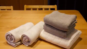 A wooden table with folded towels in shades of white and gray.