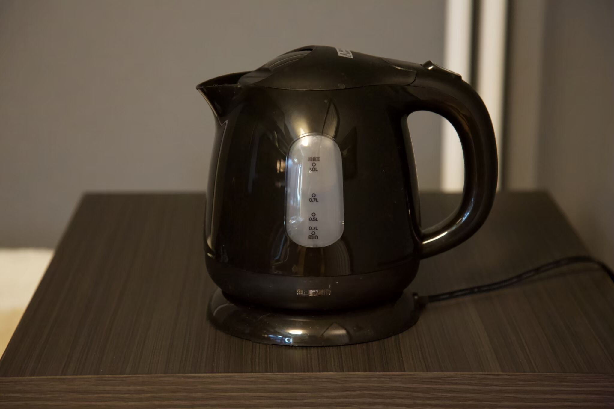 A black electric kettle on a wooden table.