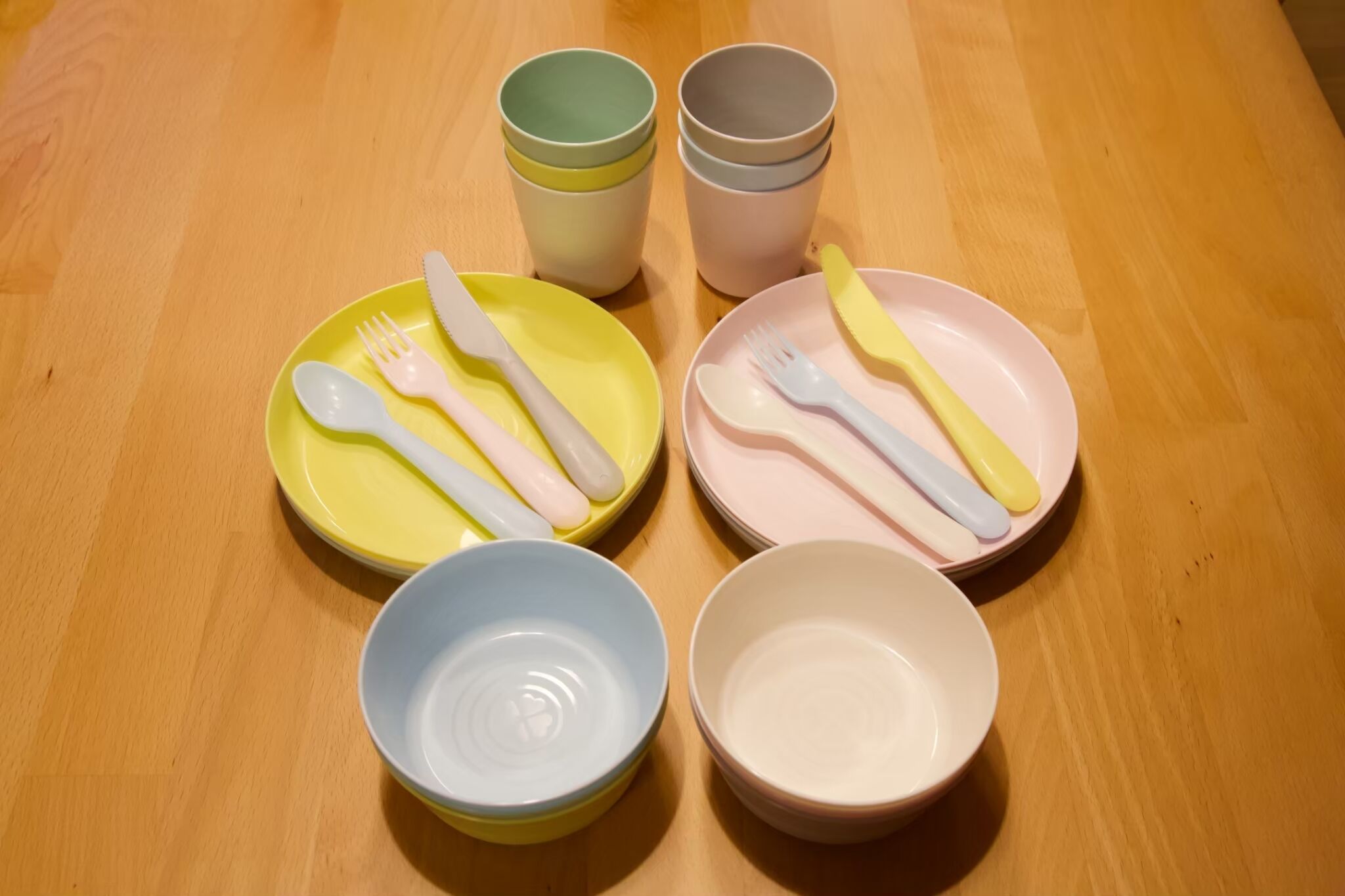 A wooden table with four sets of cutlery and bowls.
