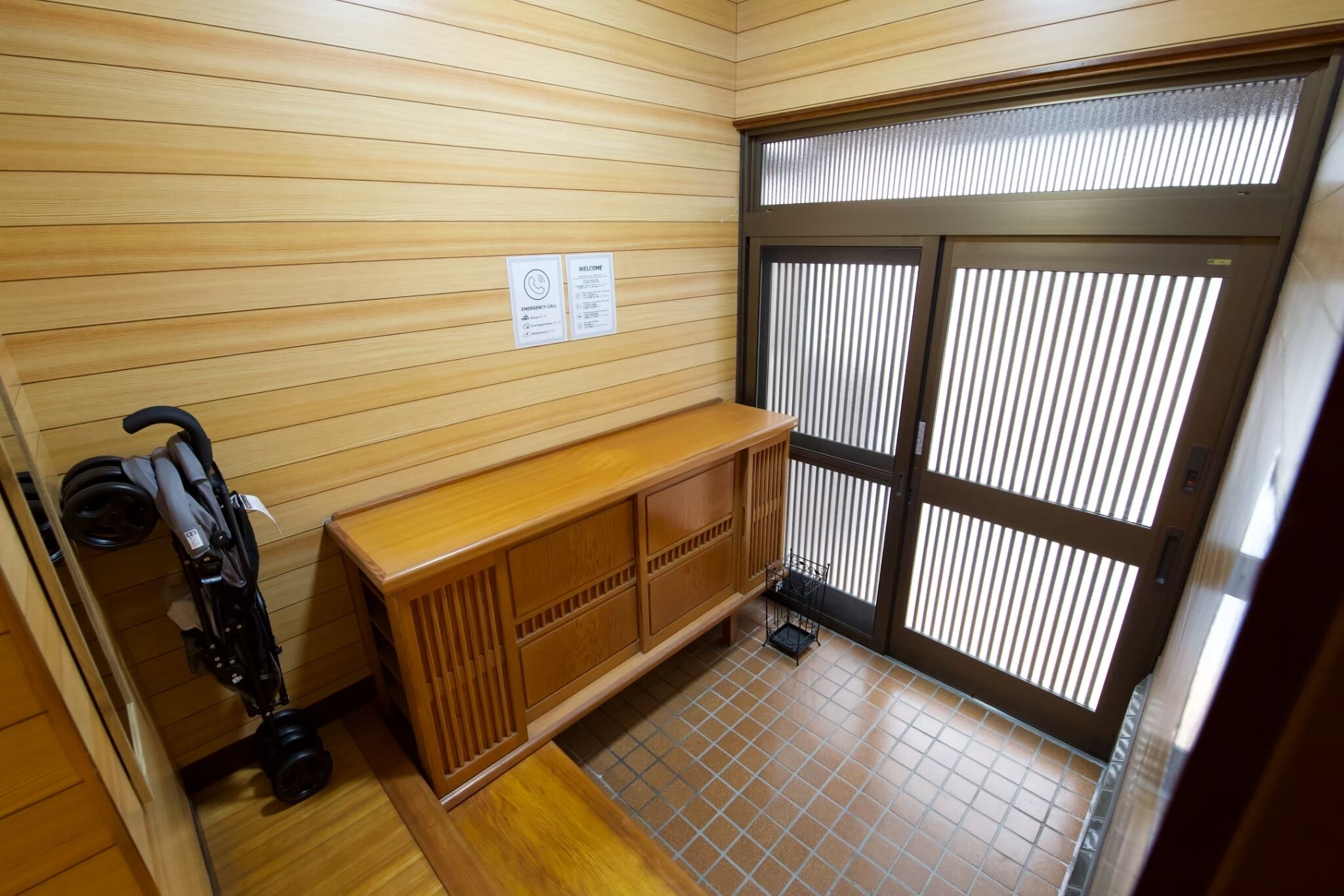 A room with wooden panel walls, a wooden cabinet, a camera, and a sliding door with blinds.