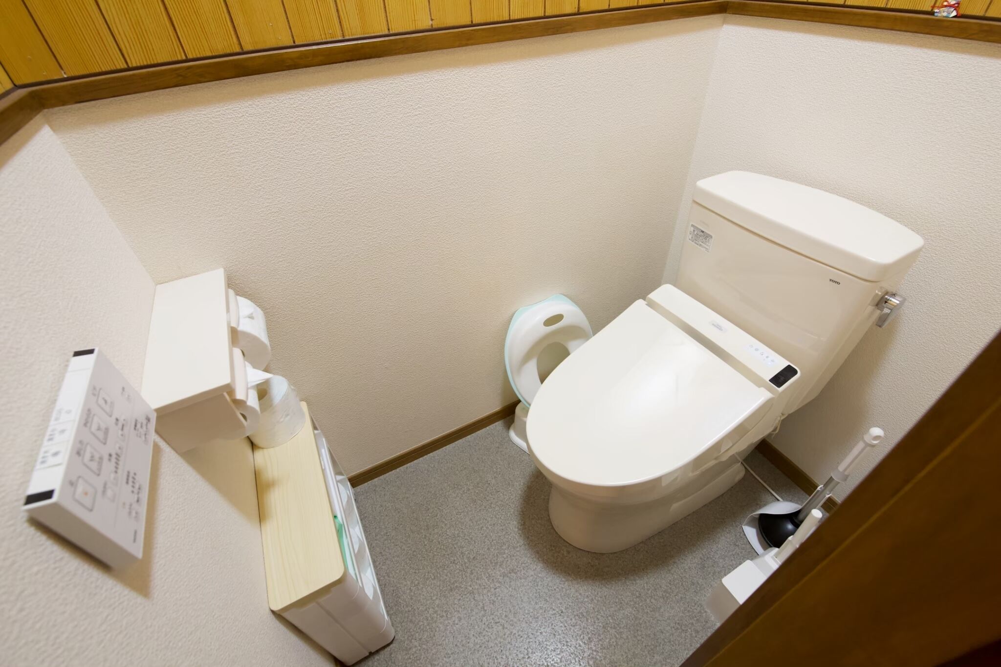 A small, compact bathroom with a toilet, a hand dryer, and a paper towel dispenser.