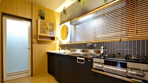 Una cocina moderna con puerta de madera, armarios empotrados, estufa y ventana con persianas.