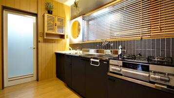 A modern kitchen with a wooden door, built-in cabinets, a stove, and a window with blinds.