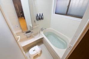 A bathroom with a bathtub, a toilet, a sink, and a mirror. There are three bottles on the wall. - B-STAY TAKAMATSU Gold Ship (Takamatsu)