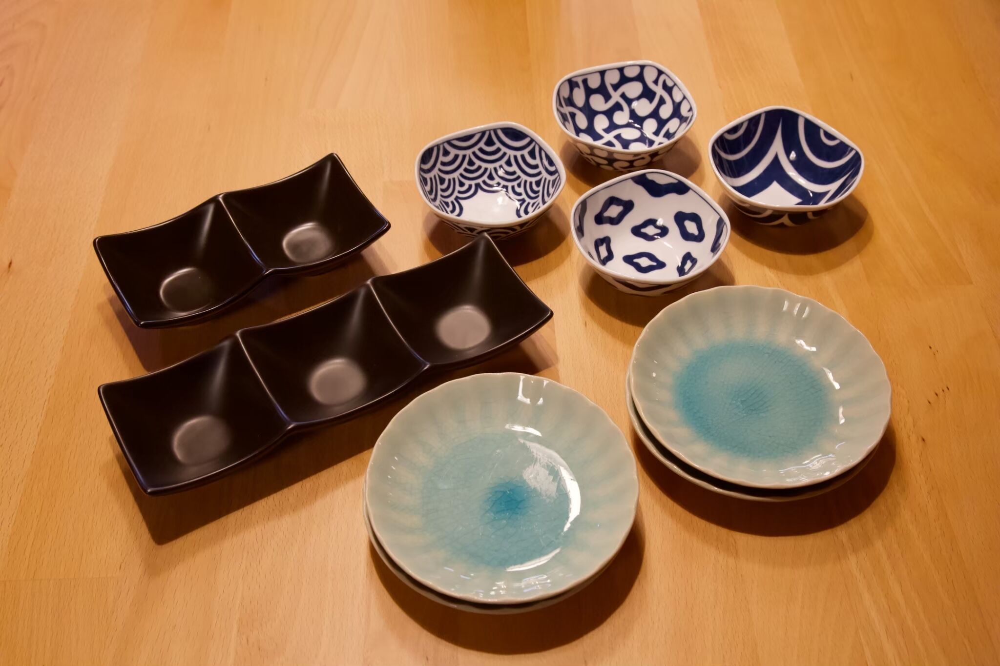 Une variété de bols et d’assiettes en céramique sont disposés sur une table en bois.