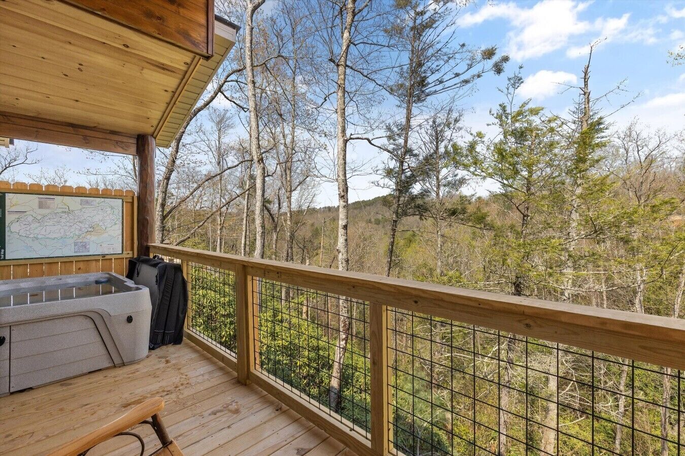 A wooden deck with a hot tub, a map, and a bench.