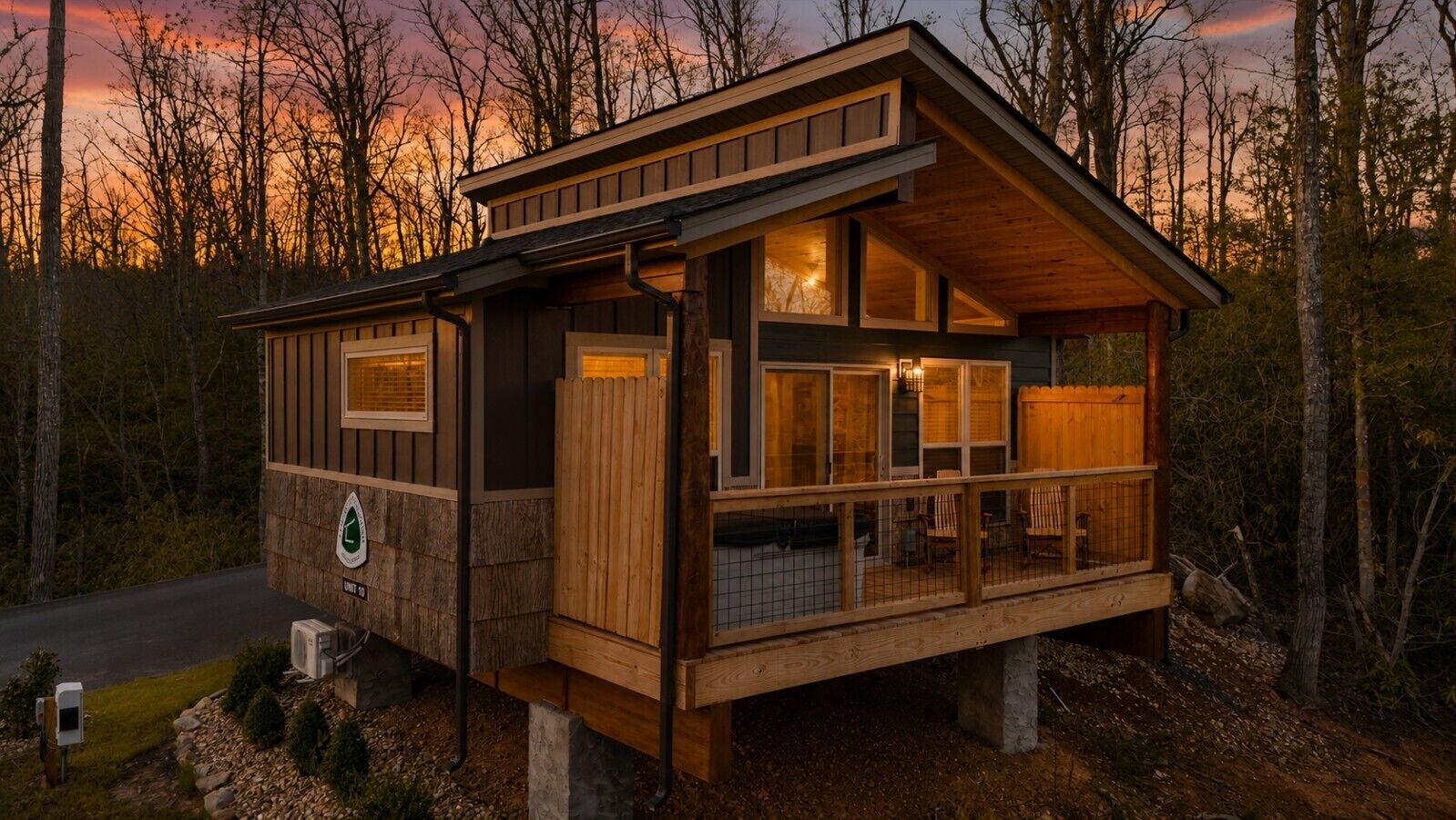 A cabin with a deck, large windows, and a sign indicating a campground.