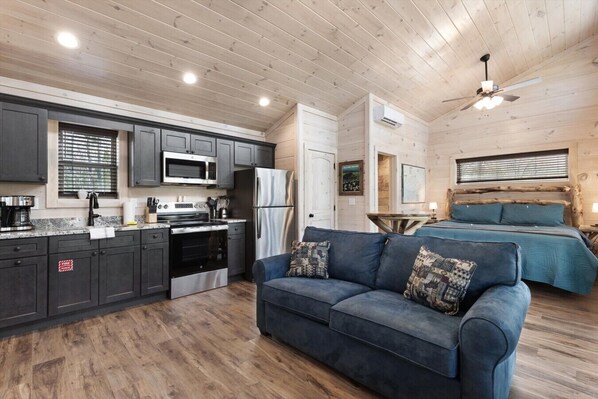 A compact living space with a kitchenette, a sofa, and a bed. - Gatlinburg 24 min | HotTub +King Bed #7 (Cosby)