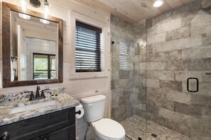 A bathroom with a marble sink, a toilet, a glass-enclosed shower, and a large mirror. - Gatlinburg 24 min + HotTub +King Bed #7 (Cosby)