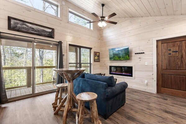 A wooden interior with a sofa, a table, a TV, and a fireplace.
