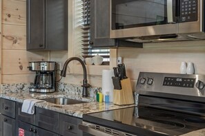 A kitchen with a stainless steel stove, a coffee maker, a microwave, and a knife block. - Gatlinburg 24 min | HotTub +King Bed #6 (Cosby)