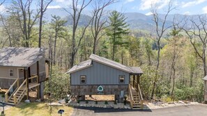 Una baita con una veranda, circondata da alberi e montagne.