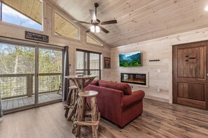 Un interior de madera con un sofá, un televisor, una chimenea y un letrero que indica Old Settlers Trail.