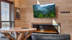 Una stanza accogliente con camino, televisione a muro e divano.