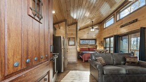 Interno di una baita in legno con cucina, zona pranzo e soggiorno con divano.