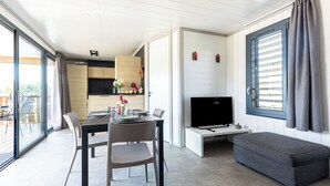Ett modernt vardagsrum med en matplats, en platt-TV och ett stort fönster med gardiner.