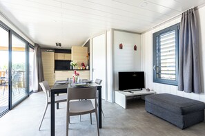 Ein modernes Wohnzimmer mit Essbereich, einem Flachbildfernseher und einem großen Fenster mit Vorhängen.