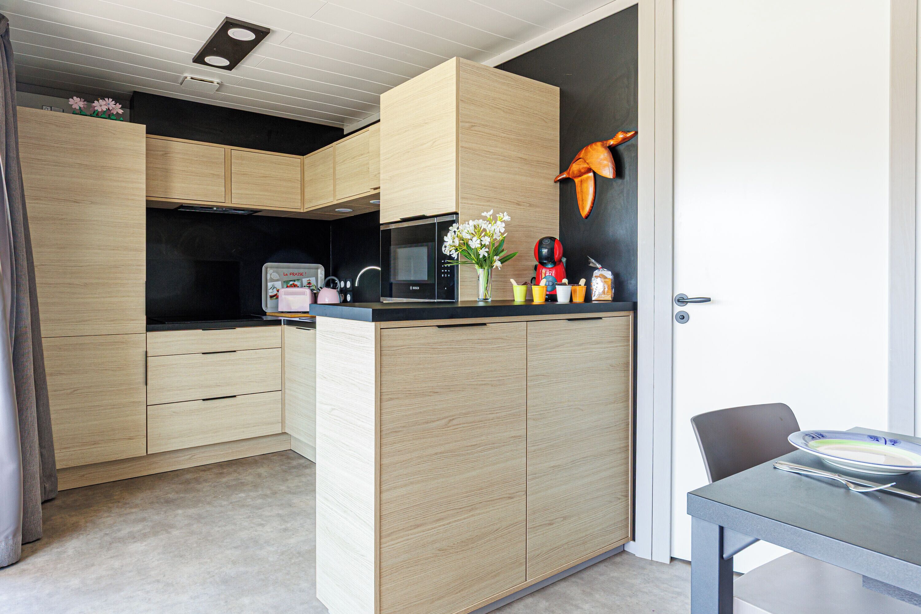 Una cocina compacta con armarios de madera, un microondas y un comedor con mesa y sillas.