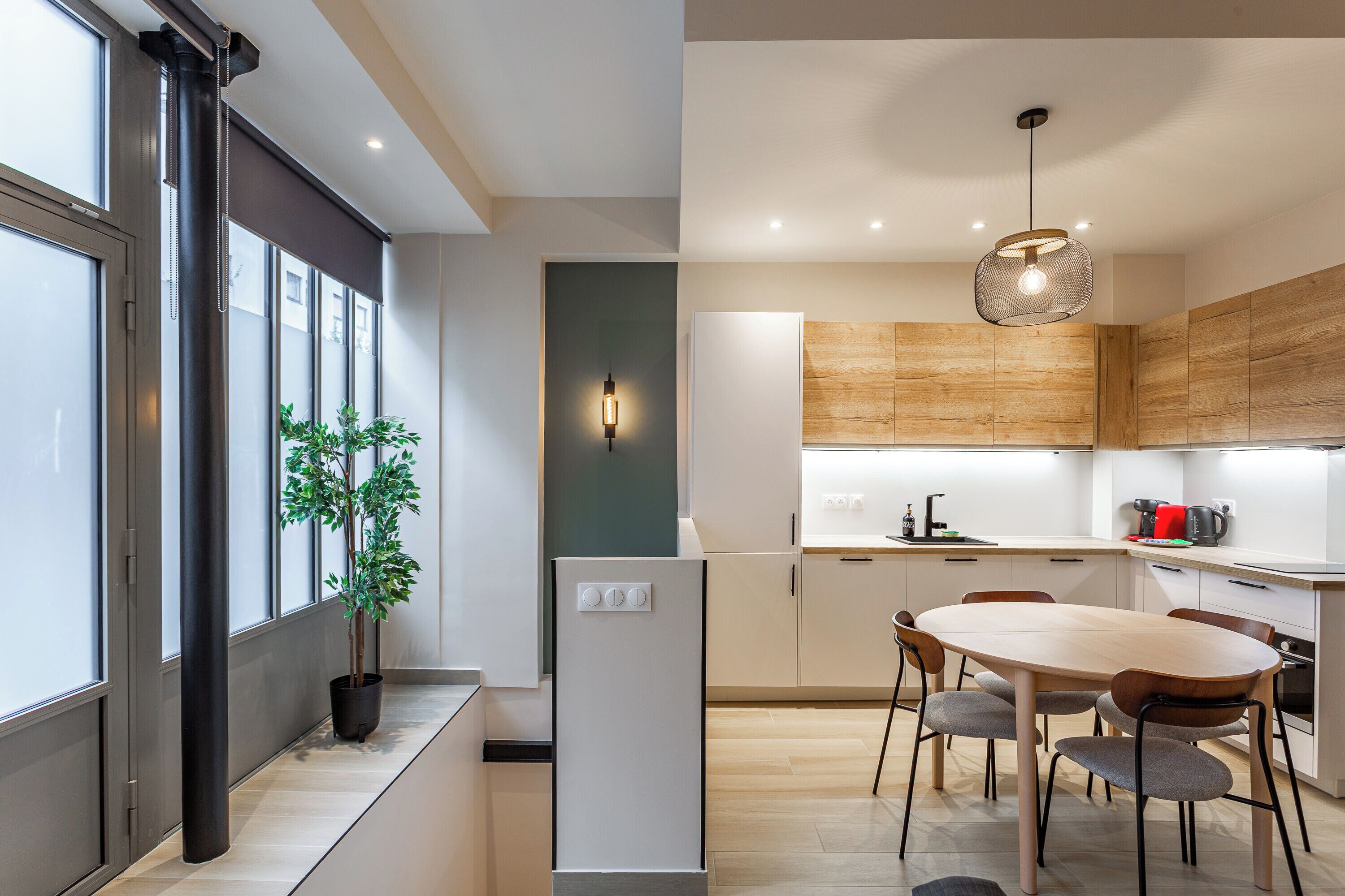 Eine moderne Küche mit Essbereich, Holzschränken, einem Einbauofen und einem Blumentopf.
