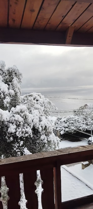 Un balcón de madera con vistas a árboles nevados y un paisaje distante.