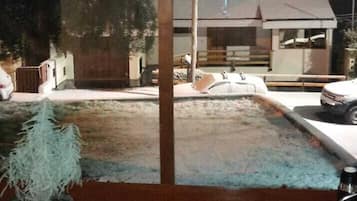 Una habitación con una mesa de madera, una planta en maceta y vista a una casa a través de una ventana.