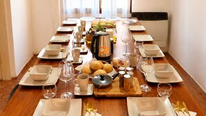 A long dining table set for a meal with plates, bowls, cutlery, and a coffee pot.