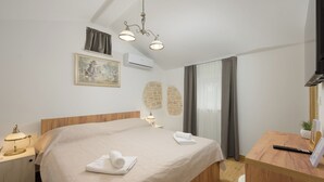 A bedroom with a bed, bedside table, lamp, air conditioning unit, and a painting on the wall. - Villa Tone i Maria (Istria - Matohanci) (Matohanci)