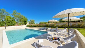 A swimming pool with lounge chairs and umbrellas, surrounded by greenery. - Villa Tone i Maria (Istria - Matohanci) (Matohanci)