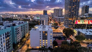Une vue urbaine avec de hauts immeubles, un bâtiment blanc imposant doté de nombreuses fenêtres, et une publicité colorée sur un autre bâtiment.