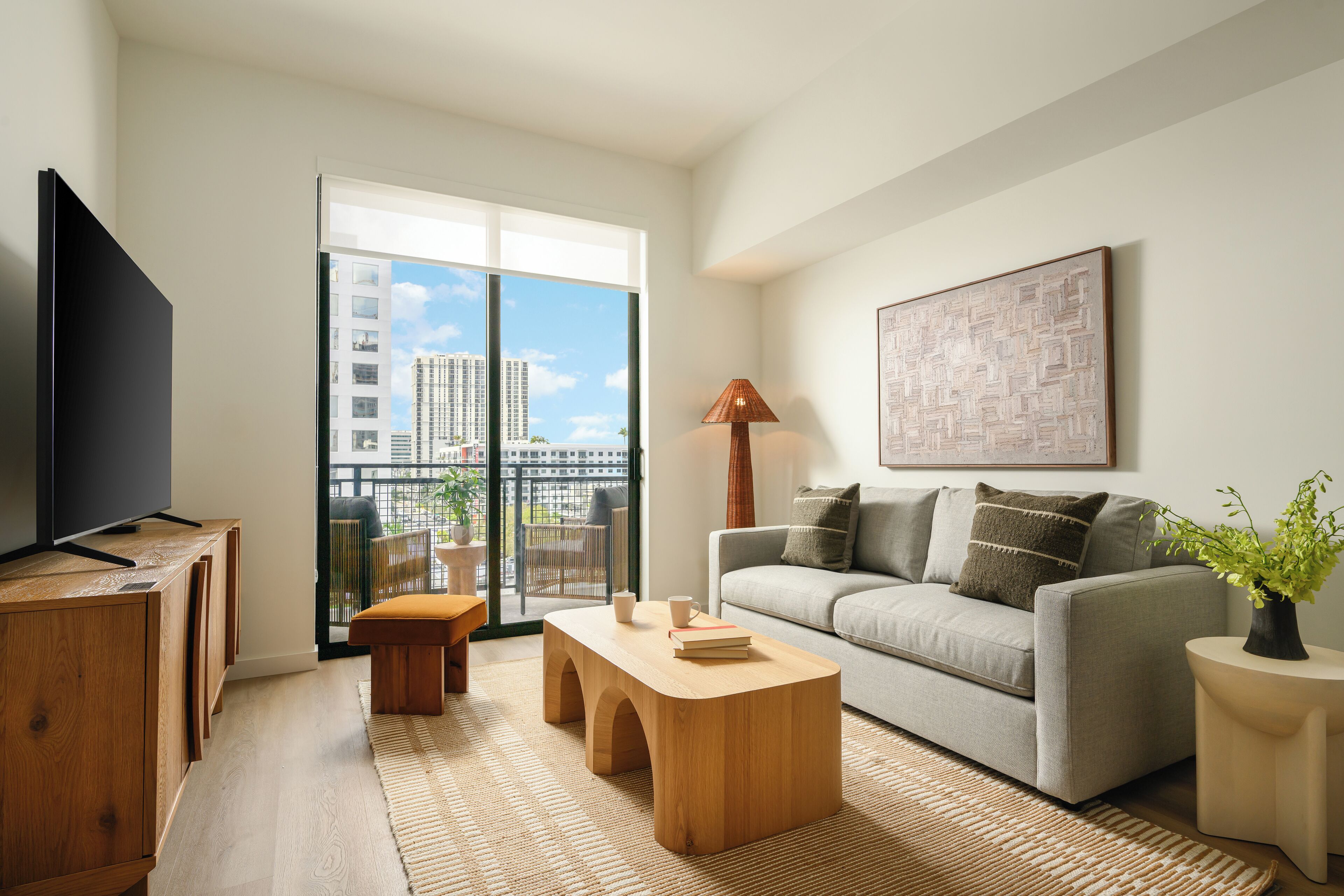 Un salon moderne avec un canapé, une table basse, un téléviseur et une vue sur la ville.