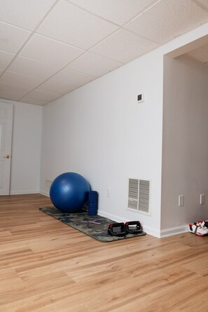 Ein Zimmer mit Holzboden, einem blauen Gymnastikball, einer Yogamatte und einem Paar Schuhe.
