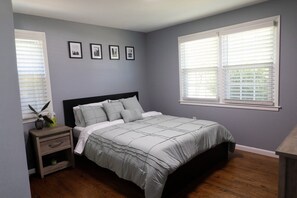 Een slaapkamer met een bed, nachtkastje en foto's aan de muur.