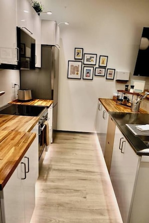 A modern kitchen with wooden countertops, stainless steel appliances, and a central island.