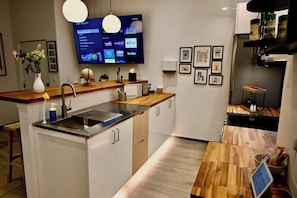 Een moderne keuken met een ingebouwde televisie, houten aanrecht en een eethoek met een houten tafel.