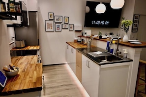 A modern kitchen with a wooden countertop, stainless steel sink, and a digital clock displaying 11:00:45 PM.