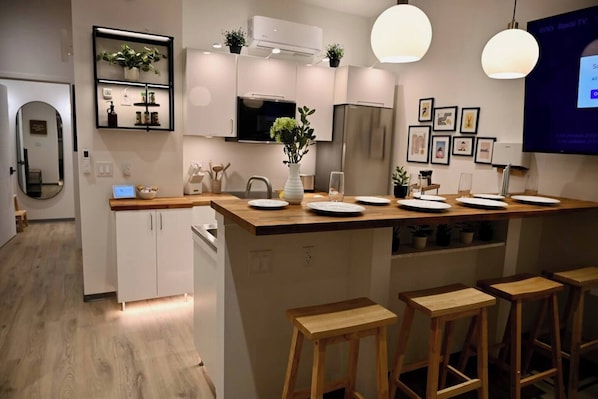 A modern kitchen with a central island, bar stools, and a dining area.