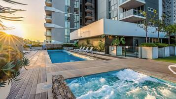 Un hotel moderno con piscina sul tetto, sedie a sdraio e vista sugli edifici circostanti.