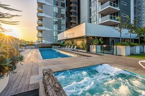 Un hotel moderno con piscina sul tetto, sedie a sdraio e vista sugli edifici circostanti.