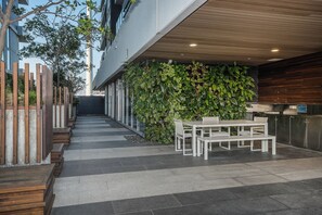 Een terras buiten met een zithoek, een verticale tuin en een moderne gevel.