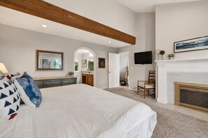 Un dormitorio con una cama grande, un aparador, un televisor y una chimenea.