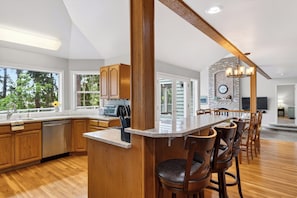 Una cocina moderna con armarios de madera, una isla grande y un comedor con taburetes de bar.